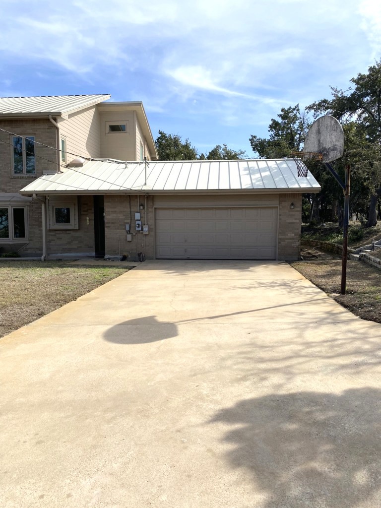 View of a driveway in front of a house with a basketball hoop on the side.